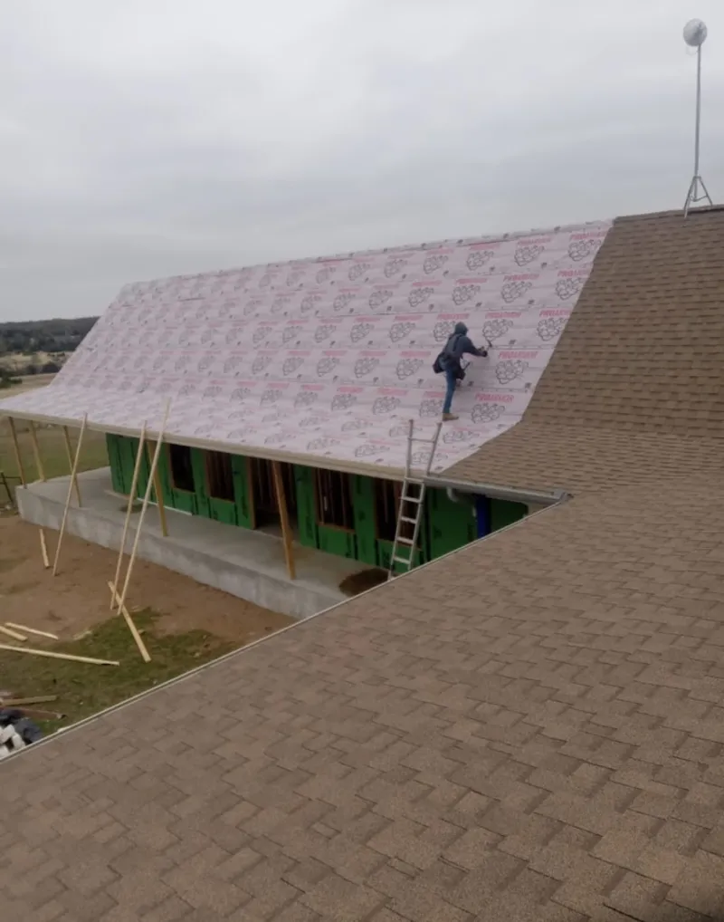 Worker preparing underlayment for a metal roof installation in La Marque